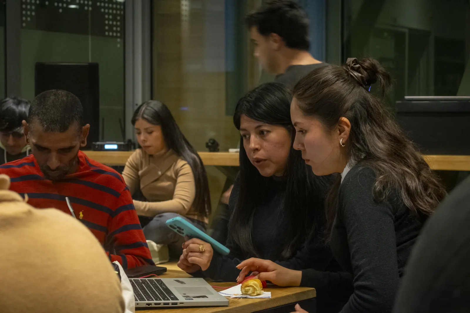 Dos personas mirando una notebook en un meetup, con una medialuna en la mesa