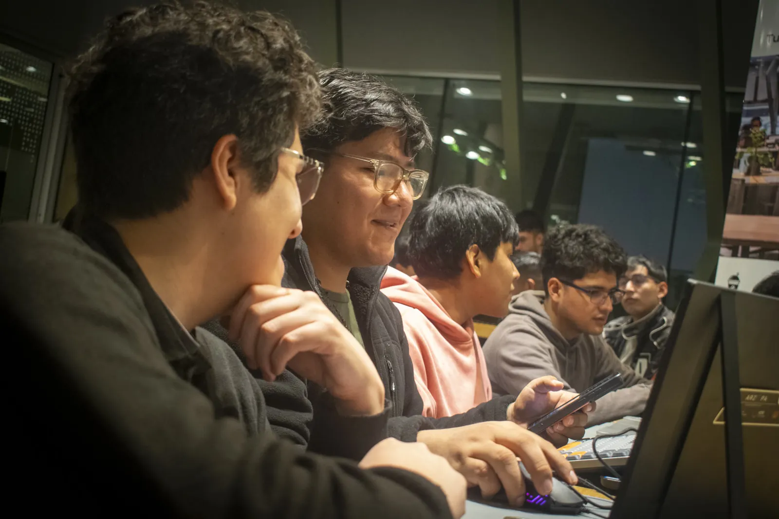 Fila de personas con notebooks en un meetup, de noche